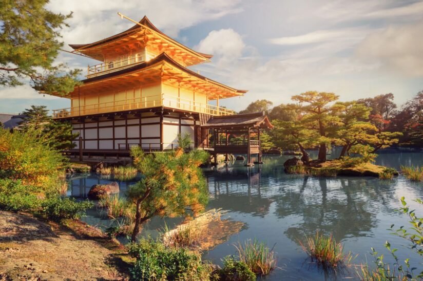 A Golden Pavilion Of Kinkaku Ji Temple Reflected In The Serene Waters Of A Lake, Surrounded By Lush Greenery