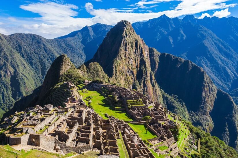 A Panoramic View Of Machu Picchu, Showcasing Ancient Incan Ruins Set Against Lush Green Mountains In Peru