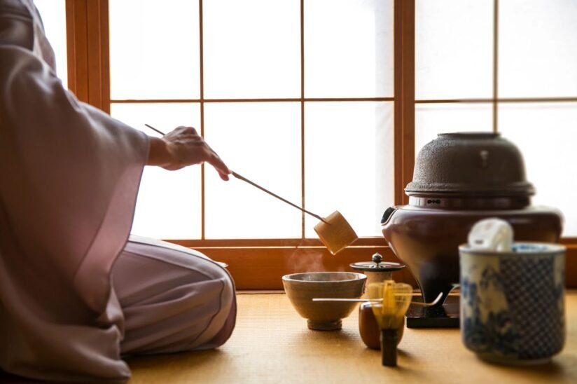 A Person In A Robe Gracefully Pours Tea Into A Bowl During A Traditional Tea Ceremony