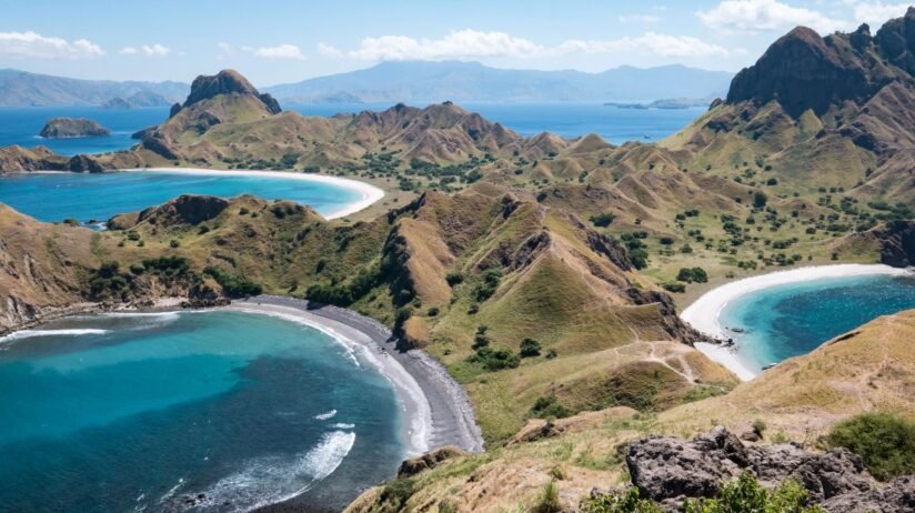 A Scenic View Of Komodo Island, Indonesia, Showcasing Its Rugged Terrain And Lush Greenery Against A Clear Blue Sky