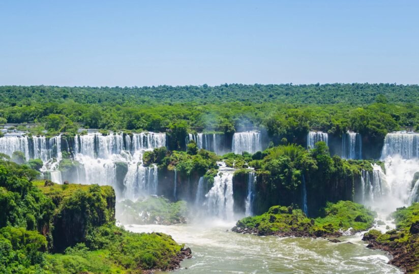 Iguazu Falls In Brazil, Showcasing A Stunning Cascade Of Water Surrounded By Lush Greenery And Mist