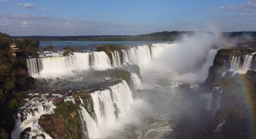 Iguazu Falls In Brazil With A Vibrant Rainbow Arching Over The Cascading Water, Showcasing Nature's Beauty
