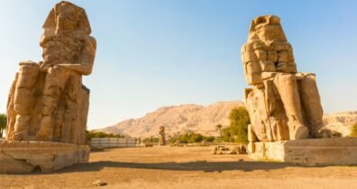 In the desert, colossi of memnon feature two impressive pharaoh statues, symbolizing ancient egyptian grandeur