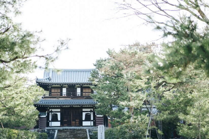 Kennin Ji Temple Nestled In A Serene Forest, Showcasing Traditional Japanese Architecture Surrounded By Lush Greenery