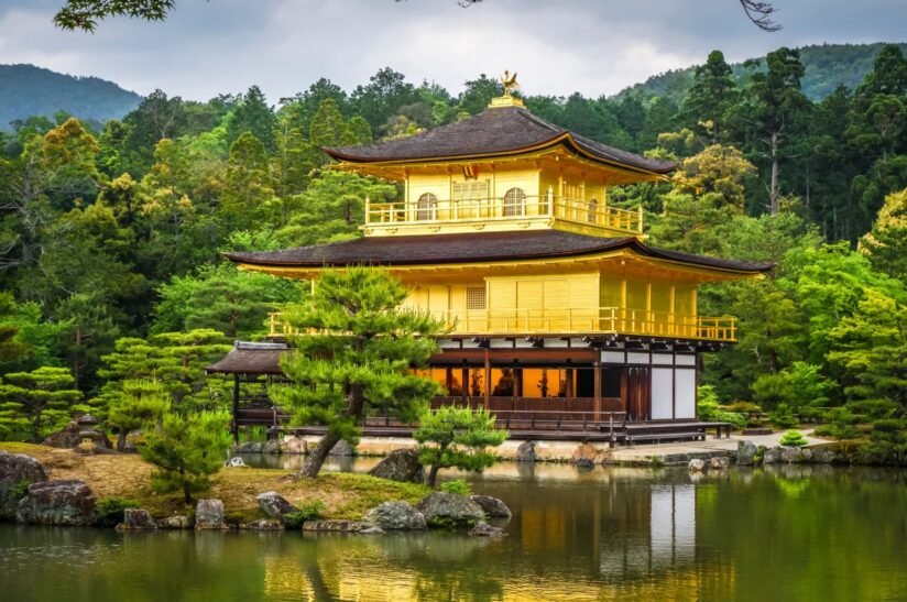 Kinkaku Ji, The Golden Temple In Kyoto, Japan, Reflects In A Serene Pond Surrounded By Lush Greenery