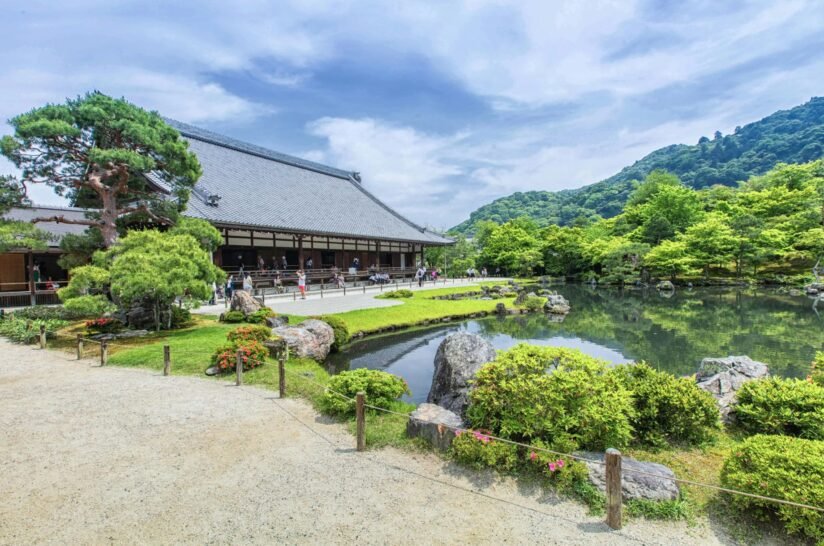 Tenryu Ji Temple Is Surrounded By A Tranquil Pond And Lush Trees, Creating A Serene Natural Setting